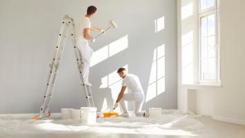 Équipe de peintres professionnels en vêtements blancs peignant un mur