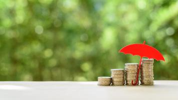 Des pièces de monnaie abritées sous un parapluie rouge miniature
