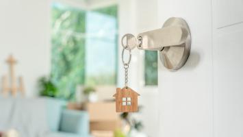 Des clés de maison sur une poignée de porte d'entrée ouverte sur l'intérieur d'une maison