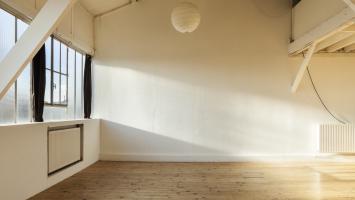 L'intérieur d'un appartement vide aux murs blancs et baigné de soleil