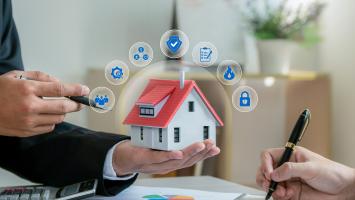 Une personne qui tient une maison miniature dans sa main