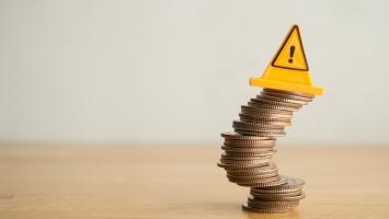 Une pile de pièces de monnaie qui penche avec un panneau de signalisation