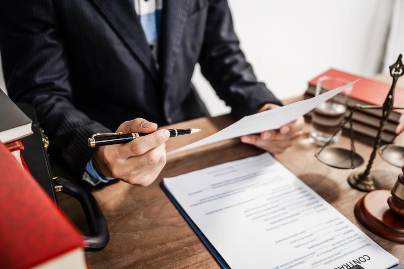 Avocat examinant un document contractuel avec un stylo à la main.