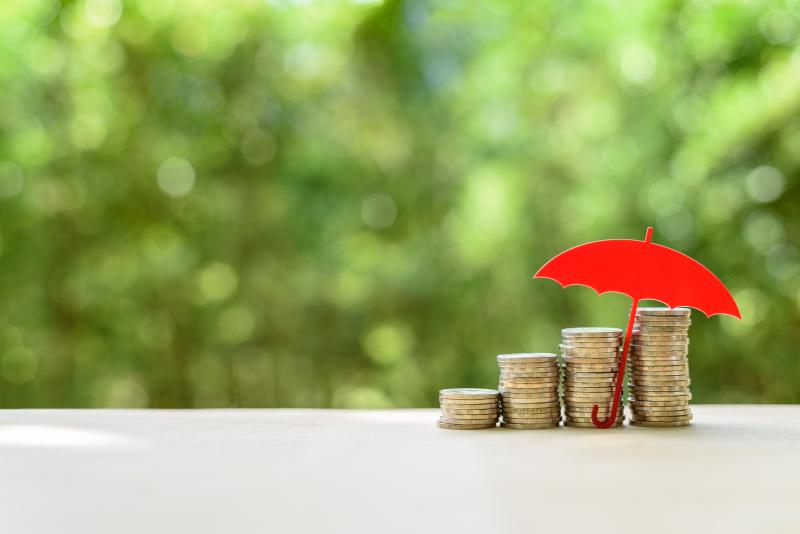 Des pièces de monnaie abritées sous un parapluie rouge miniature