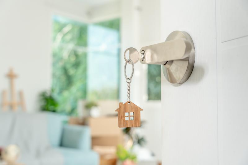 Des clés de maison sur une poignée de porte d'entrée ouverte sur l'intérieur d'une maison