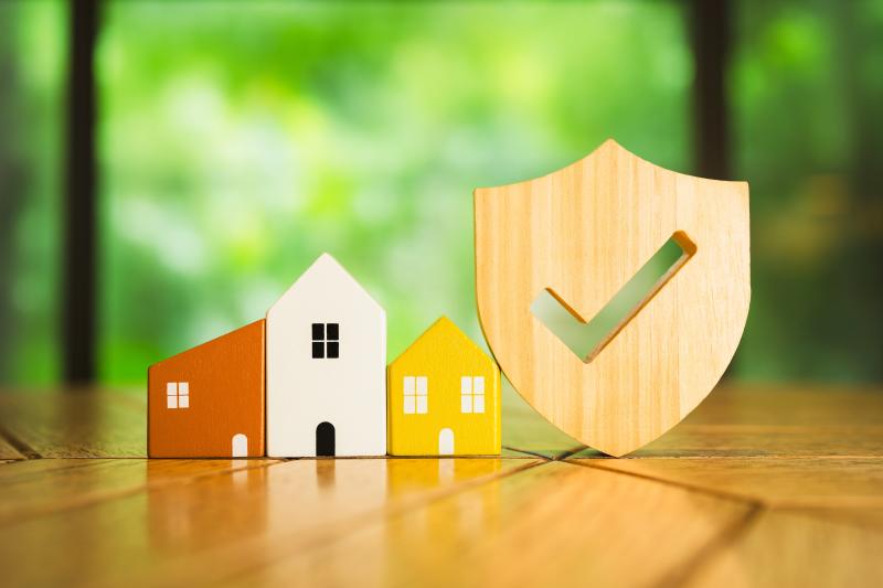 Des maisons miniatures colorées en bois et un bouclier