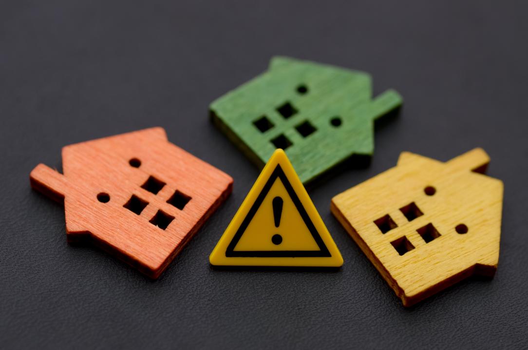 Trois maisons miniatures avec signe d'avertissement d'exclamation concept de risque et de danger pour l'immobilier