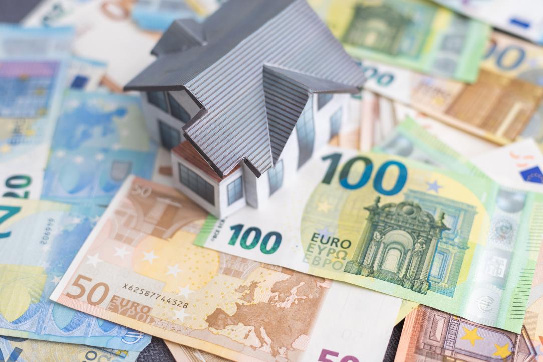 Une maison miniature posée sur des billets de banque en euros