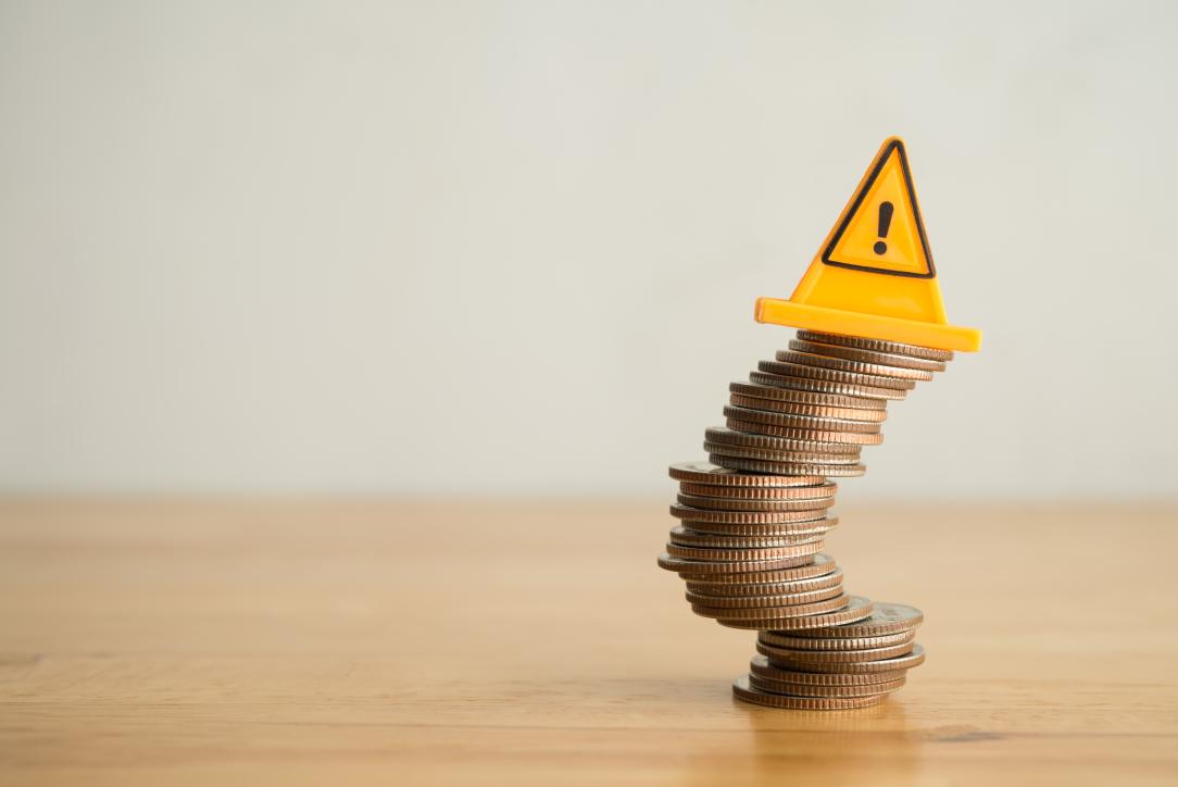 Une pile de pièces de monnaie qui penche avec un panneau de signalisation