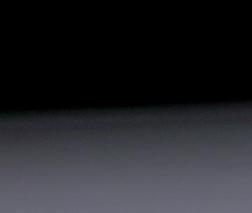 Une femme qui tient des clés à côté d'une maison miniature colorée posée sur un bureau