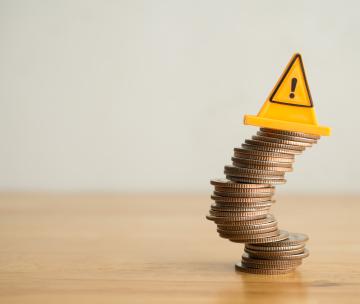 Une pile de pièces de monnaie qui penche avec un panneau de signalisation